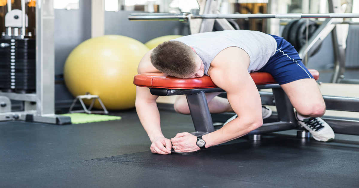 Tired young man lying on a gym bench